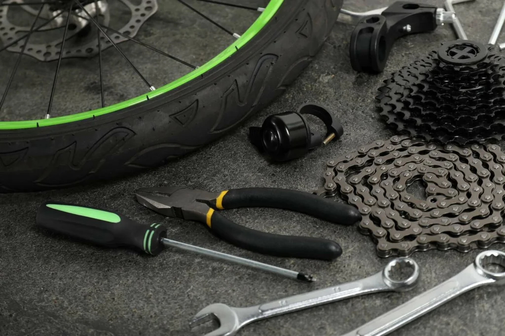 Herramientas básicas y cadena de bicicleta junto a una rueda durante el cuidado y mantenimiento de una bici, necesarias para la reparación de bicis y el correcto funcionamiento de sus componentes.