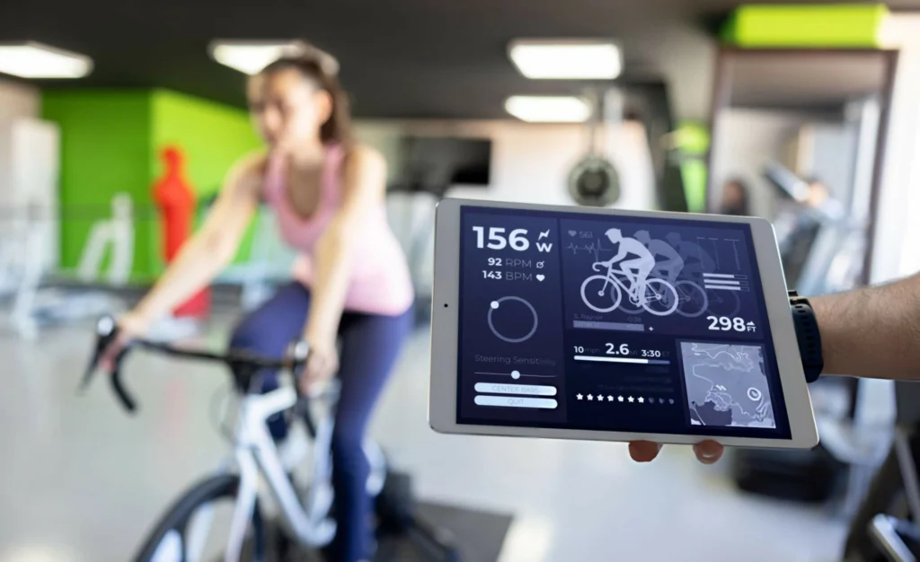 Persona iniciando una rutina de  indoor en bicicleta estática profesional con accesorios deportivos.