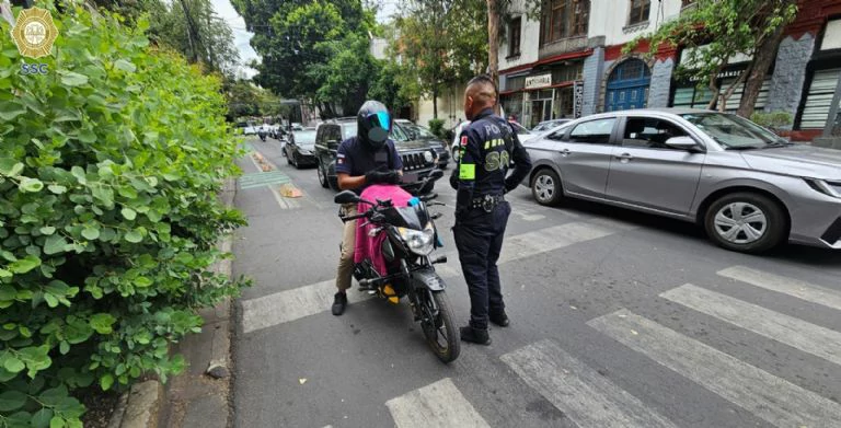 Oficial de tránsito aplicando multa por invadir la ciclovía en CDMX, sanción de hasta 30 UMAs y posible remisión del vehículo al corralón.