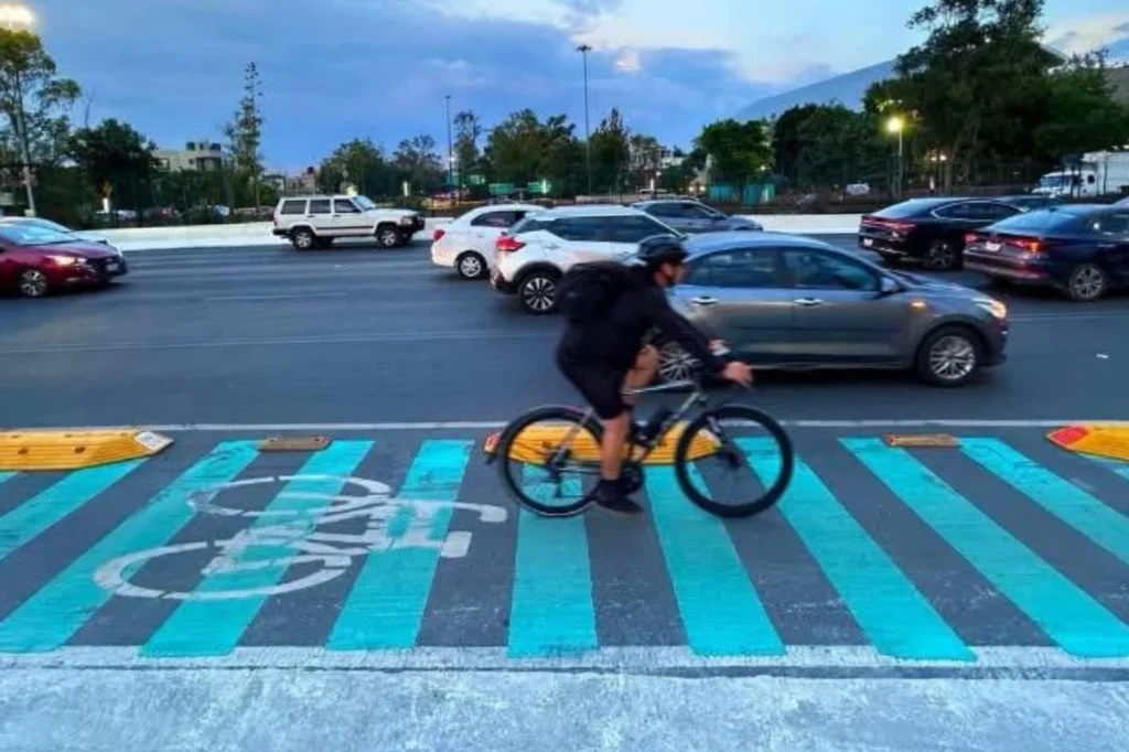 Carril para bicicletas con cruce señalizado que mejora la movilidad urbana entre autos y ciclistas
